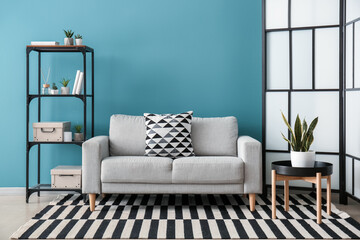 Interior of living room with folding screen, sofa and shelving unit