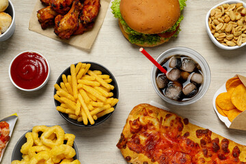 French fries, onion rings and other fast food on white wooden table, flat lay