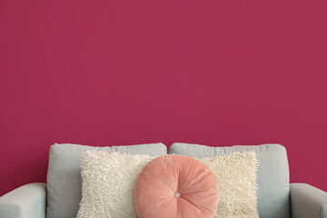 Grey sofa with cushions near pink wall