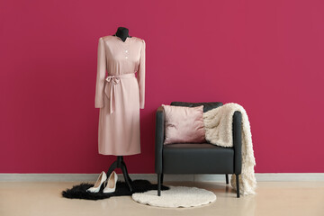 Black armchair and mannequin near pink wall in room