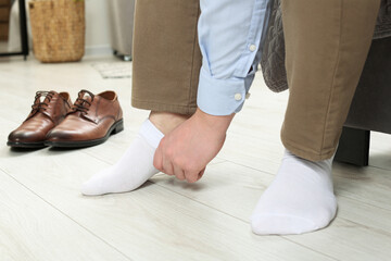 Man putting on white socks at home, closeup