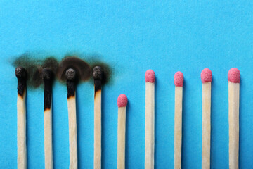 Burnt and whole matches on light blue background, closeup. Stop destruction by breaking chain reaction concept
