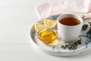 Aromatic herbal tea with thyme, honey and lemons on white wooden table, space for text