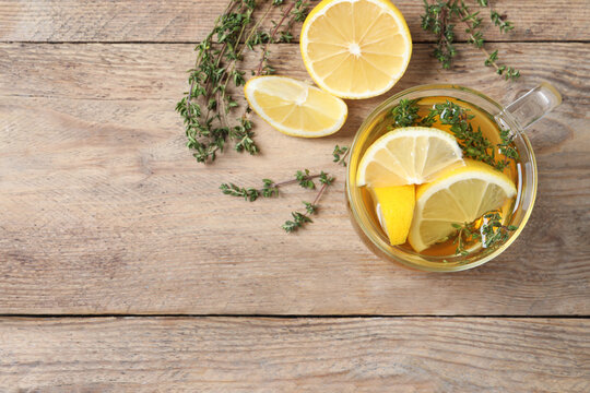 Aromatic herbal tea with thyme and lemon on wooden table, flat lay. Space for text