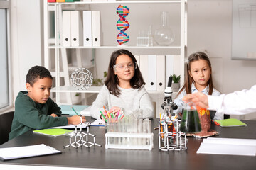 Cute little children with teacher having Chemistry in science classroom