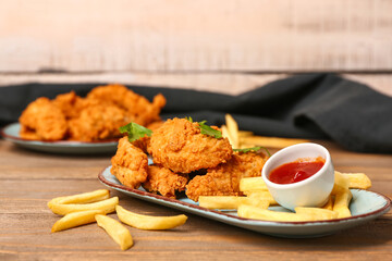 Plate of tasty nuggets, sauce and french fries on wooden table