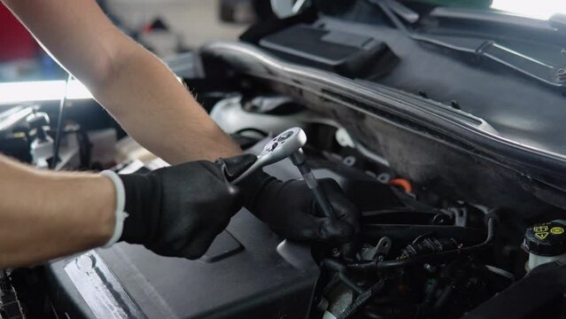 Closeup hand and spanner. Caucasian male mechanic repairs car in garage. Car maintenance and auto service garage concept