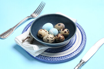 Table setting with Easter eggs and willow branches on blue background, closeup