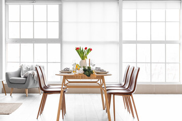 Beautiful table setting for International Women's Day celebration with different flowers in interior of light room