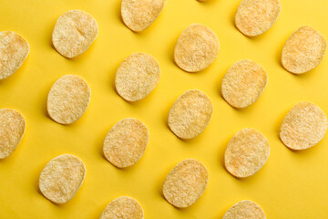 Many delicious potato chips on yellow background