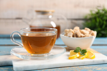Board with cup of tasty green tea, lemon slices and cane sugar on color wooden table