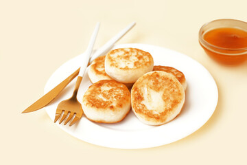 Plate with tasty cottage cheese pancakes and jam on color background