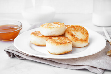 Plate of tasty cottage cheese pancakes with jam on light background, closeup