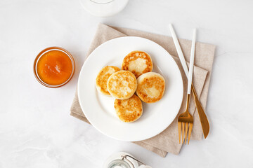 Plate of tasty cottage cheese pancakes with jam on light background