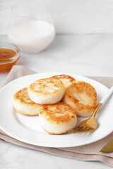 Plate with tasty cottage cheese pancakes on light background, closeup