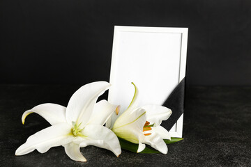 Blank funeral frame and beautiful lily flowers on dark background
