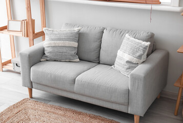 Grey sofa with cushions near white wall
