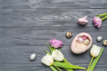Composition with Easter quail eggs, tulip flowers and bunny on grey wooden background