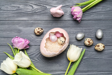 Composition with Easter quail eggs, tulip flowers and bunny on grey wooden background