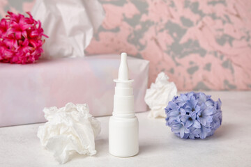 Obraz na płótnie Canvas Nasal drops with flowers and tissues on table near grunge wall. Seasonal allergy concept