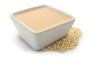 Ceramic bowl of tasty tahini and sesame seeds on white background