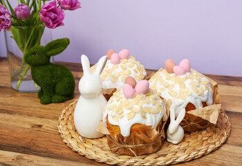 Obraz na płótnie Canvas Easter cakes and bunnies on kitchen counter near lilac wall