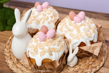 Easter cakes with painted eggs and bunnies on wicker mat, closeup