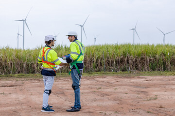 Team engineer wearing safety uniform discussed plan working on wind turbine renewable energy power wind. technology protect environment reduce global warming problems.