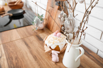 Vase of willow branches with Easter decorations on kitchen counter, closeup