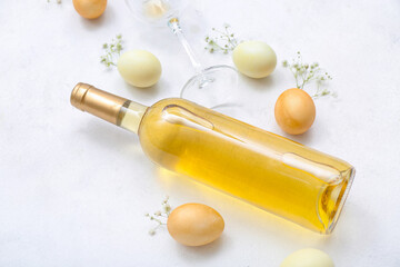 Composition with bottle of wine, glass, Easter eggs and gypsophila flowers on light background