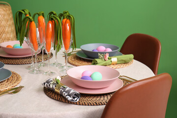 Stylish Easter table setting with decorative carrots near color wall, closeup