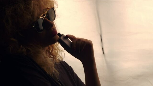 silhouette of a person with a sunglasses smoking vapear