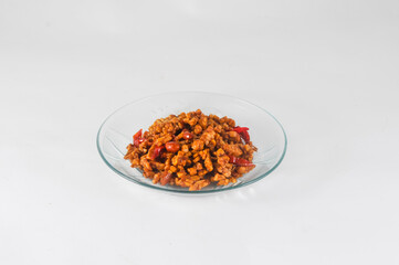 sliced tempeh fried dry with chilies and peanuts or orek tempe served on a small plate isolated on a white background