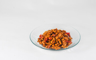 sliced tempeh fried dry with chilies and peanuts or orek tempe served on a small plate isolated on a white background
