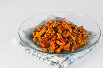 sliced tempeh fried dry with chilies and peanuts or orek tempe served on a small plate with a...