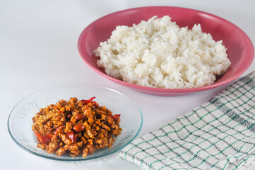 sliced tempeh fried dry with chilies and peanuts or orek tempe served on a small plate with a napkin isolated on a white background