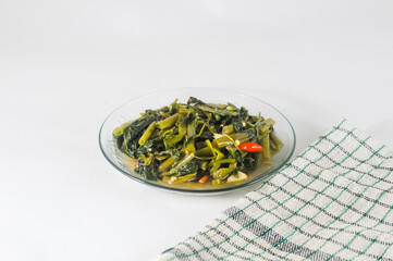 stir-fried water spinach dishes are served on a small plate with a napkin isolated on a white background