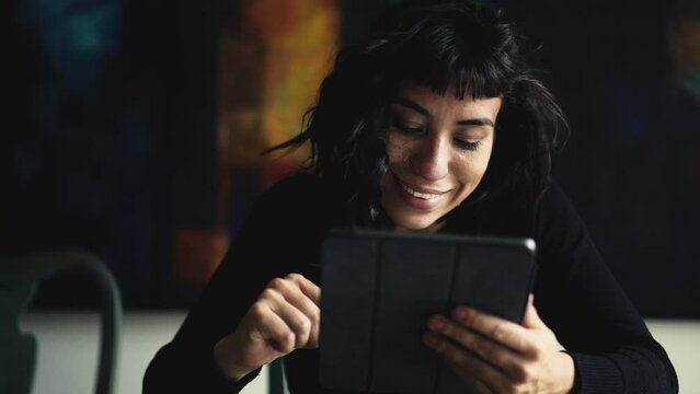Happy Hispanic woman using tablet device browsing internet online