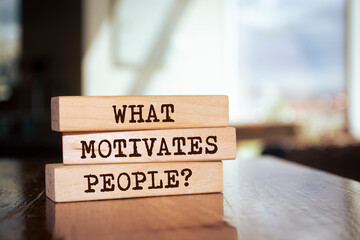 Wooden blocks with words 'WHAT MOTIVATES PEOPLE?'.