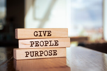 Wooden blocks with words 'GIVE PEOPLE PURPOSE'.