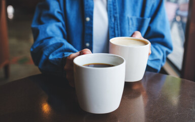 Closeup image of a woman holding and serving two cups of hot coffee