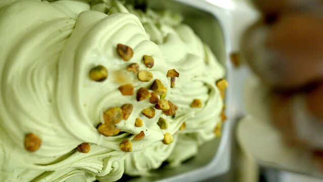 factory worker putting chunk of pistachio into a tray of pistachio ice cream