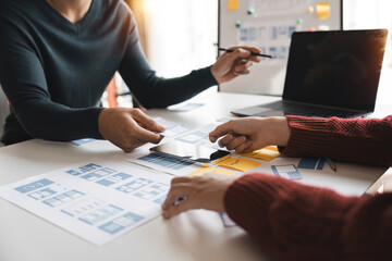 Close up ux developer and ui designer brainstorming about mobile app interface wireframe design at modern office. Creative digital development agency