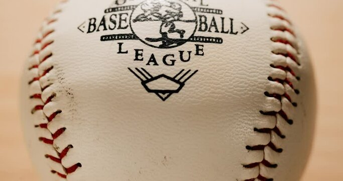 dirty used Official baseball league ball rotating close up with bright warm background