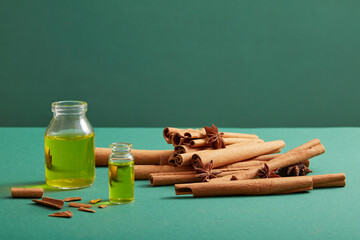 Front view of glass bottles without label, containing essential oils, cinnamon sticks and anise on blue background. Mockup scene for product of cinnamon extract - natural herbal good for health.