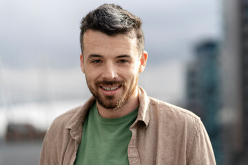 Fototapeta premium Authentic portrait of handsome smiling hispanic man wearing casual clothing looking at camera standing on the street