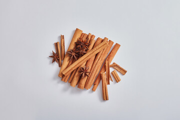 Minimal art concept with cinnamon sticks and anise (illicium verum) isolated on light background. These are herbs good for health, heart, skincare and haircare. Top view, flat view.