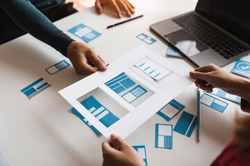 Close up ux developer and ui designer brainstorming about mobile app interface wireframe design at modern office. Creative digital development agency