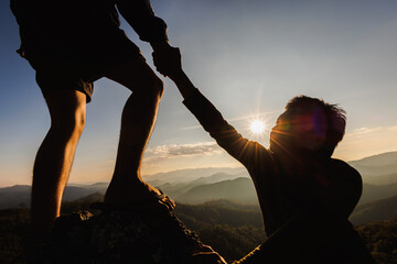 Silhouette of hiker helping each other hike up a mountain at sunset. People helping and, team work concept. - obrazy, fototapety, plakaty