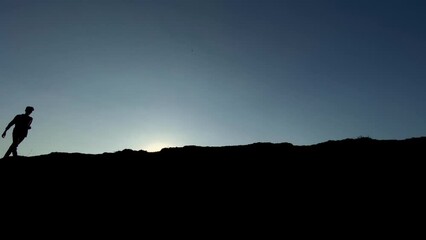 A black silhouette of a lonely man hiking over a meadow path, with moonlight reflecting on his jacket. Mental health concept